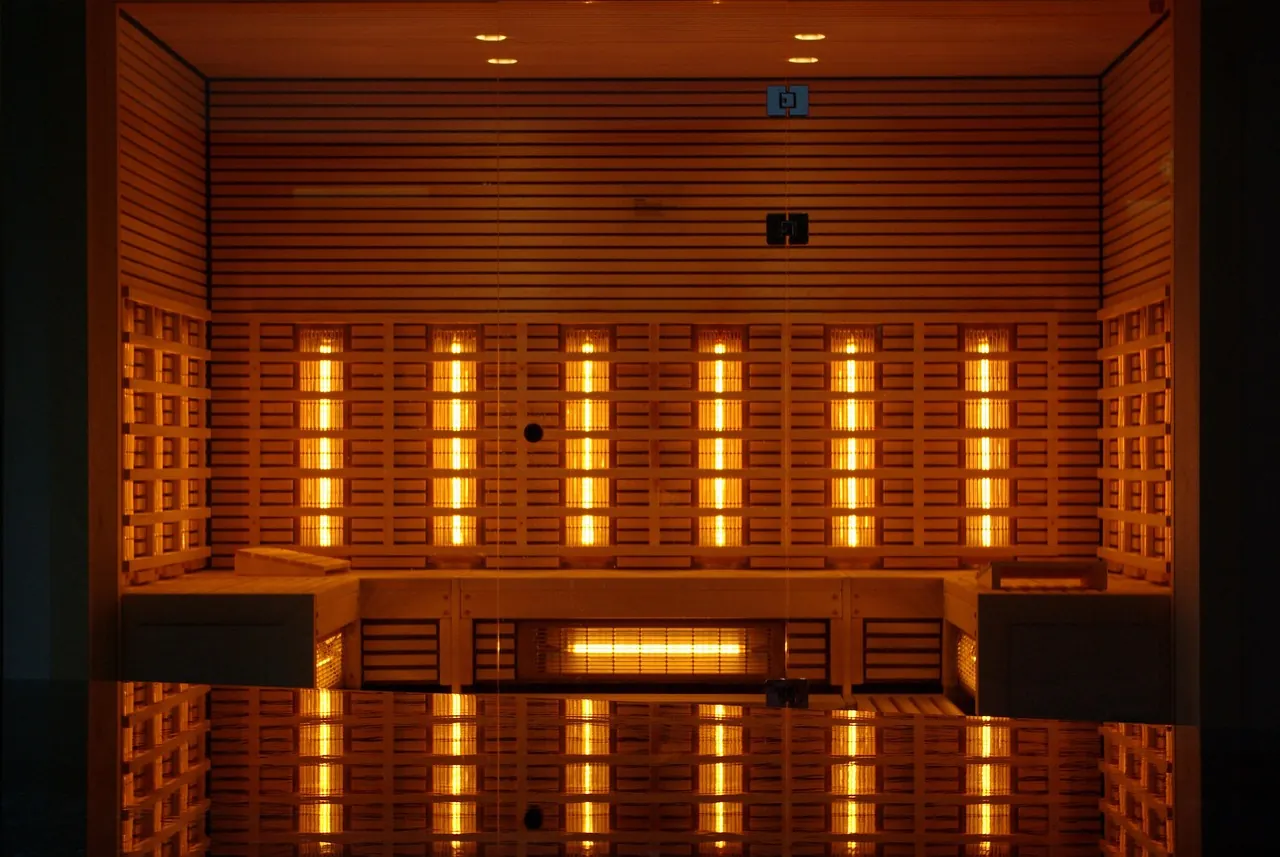 Wooden interior of an infrared sauna cabin with glowing vertical heating lamps and benches
