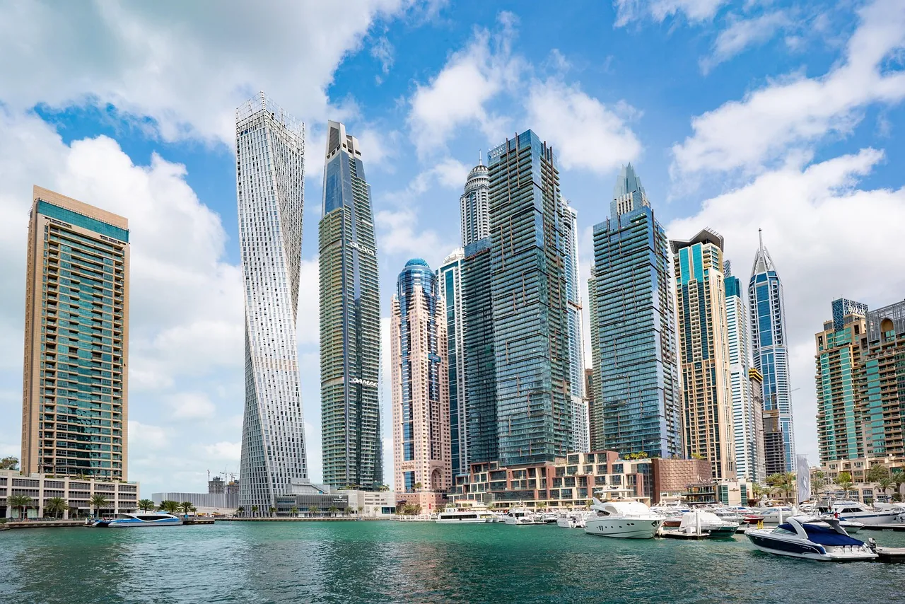 Dubai Marina towers under a blue sky with boats in the marina
