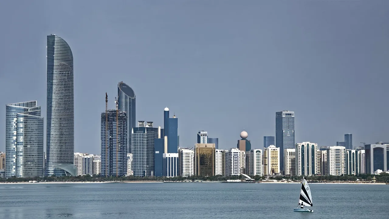 The Abu Dhabi skyline across the water, with a small sailing boat in the foreground