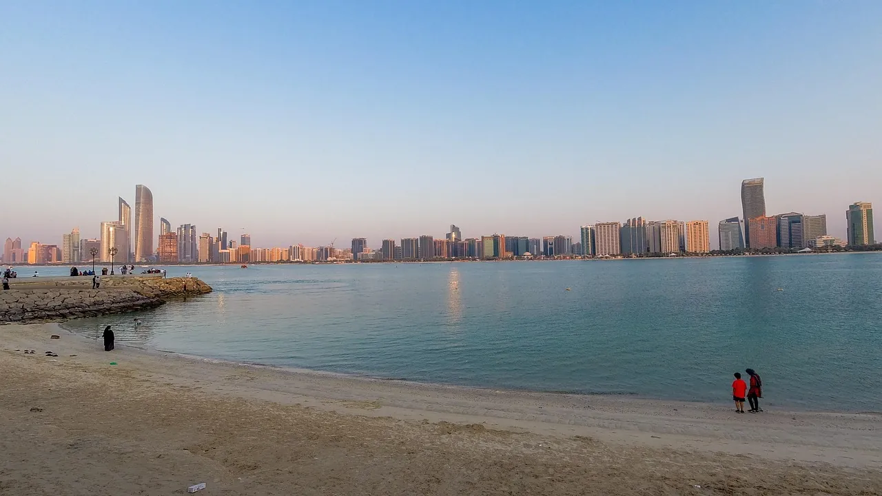 Abu Dhabi's waterfront towers seen across a calm bay from the beach