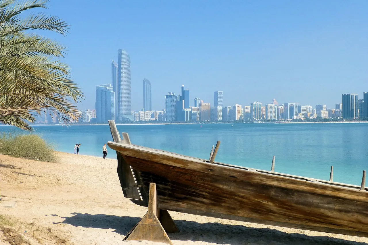 A wooden dhow on a Dubai beach with the city skyline beyond